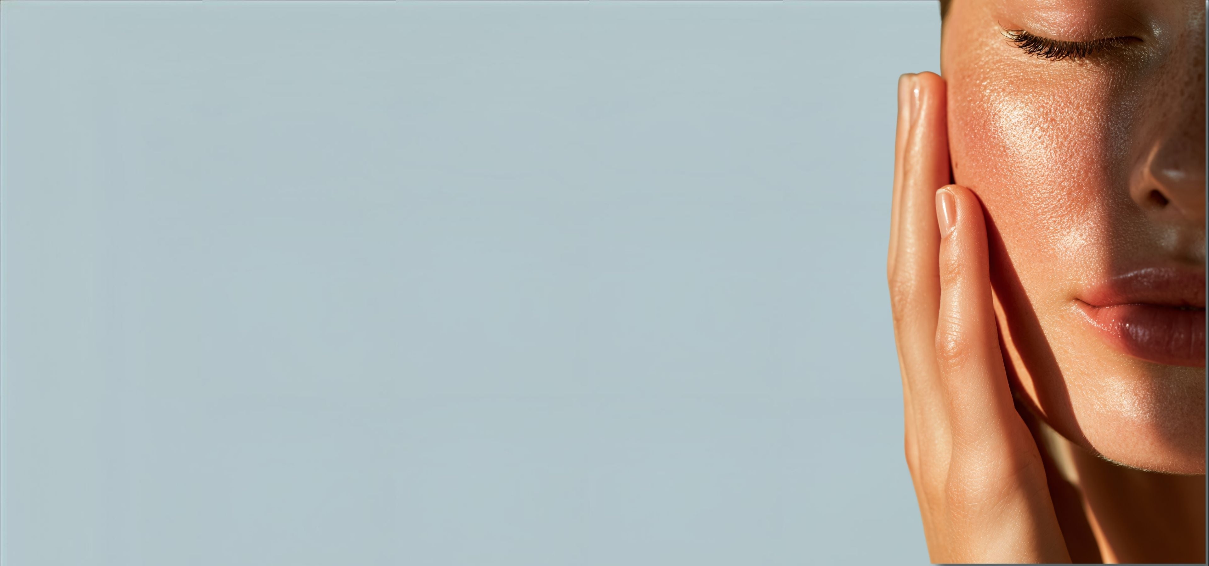 Close-up of a person's face with hand on a light gray background