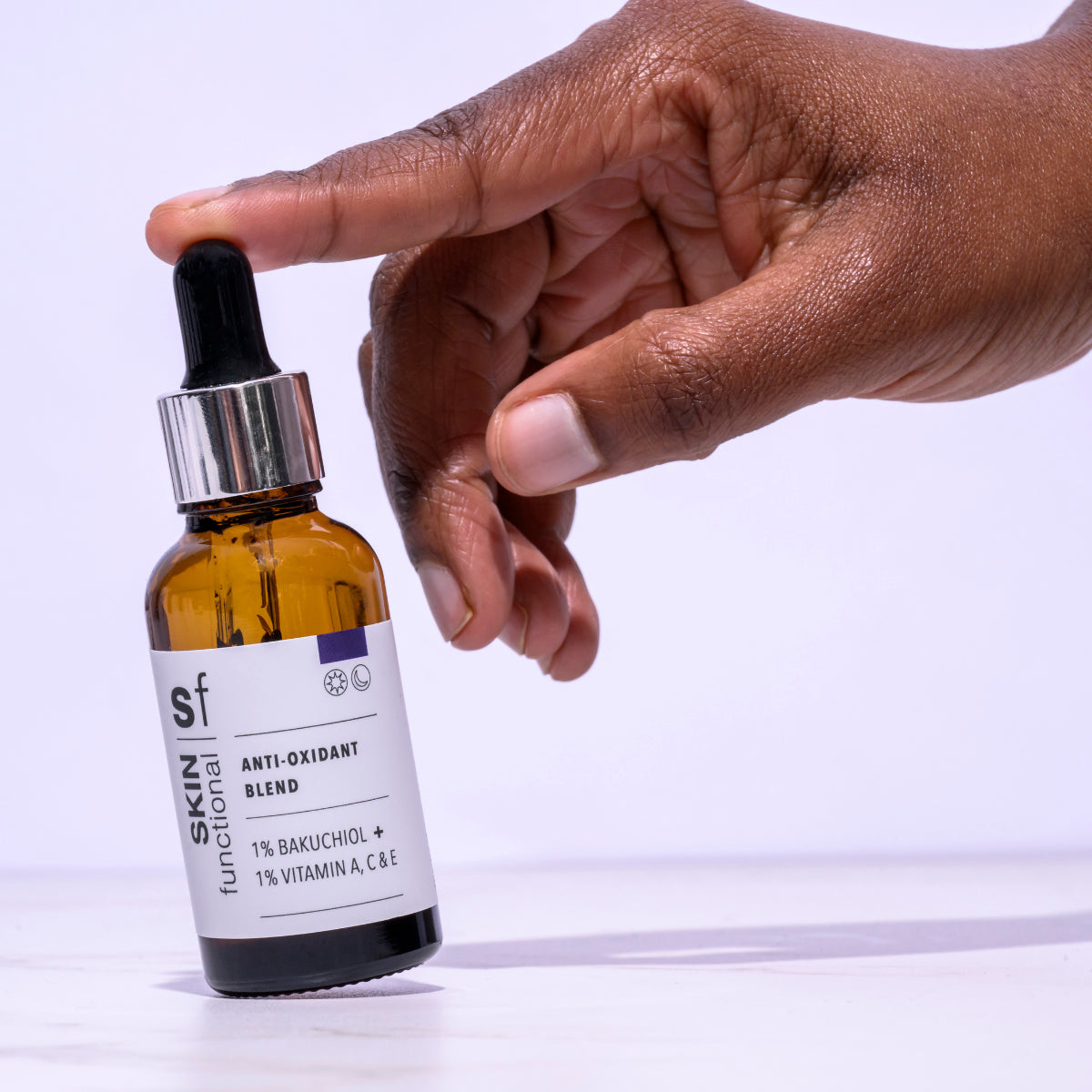 Hand holding a Skin Functional Ani-Oxidant Blend dropper bottle with a white background