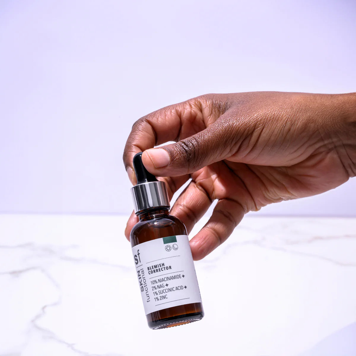 Hand holding a Skin Functional Blemish Corrector bottle 